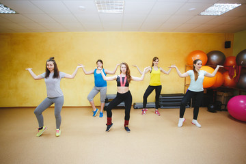 smiling people with coach dancing zumba in gym or studio