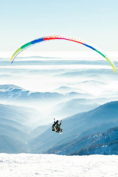 Paragliders launched into air from snowy slope of a mountain