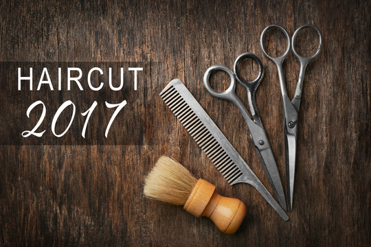 Vintage barber equipment and text HAIRCUT 2017 on wooden background