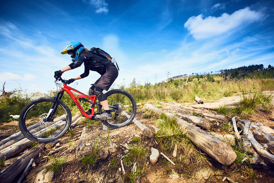 Female Mountain Bike cyclist riding track at sunny day in European mountains