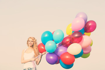 Fototapeta na wymiar Young woman with colorful balloons on sky background