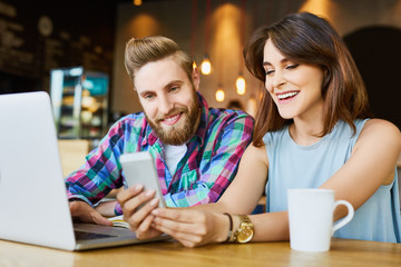 Happy couple meeting in cafe working with laptop and smartphone