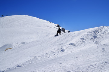 Fototapeta na wymiar Snowboarder in snow park at ski resort on sunny winter day