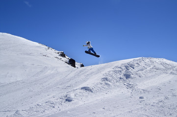 Fototapeta na wymiar Snowboarder jumping in snow park at ski resort on sunny winter d