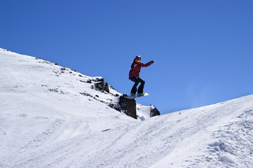 Naklejka na ściany i meble Snowboarder jumping in snow park at ski resort on sun winter day