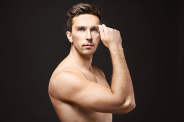 Young man touching his face on black background