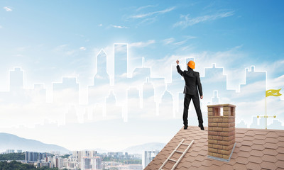 Man architect draw silhouette of modern city on blue sky. Mixed media