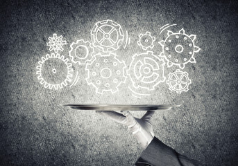 Waiter hand with empty silver tray and drawn gears concept