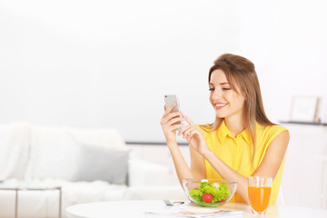 Obraz na płótnie Canvas Young beautiful woman having breakfast and using smart phone
