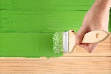 Decorator painting wood with green paint