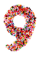 Figure nine "9" made up by plastic particles of different colors isolated on white background.