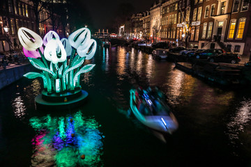 Fototapeta premium AMSTERDAM, NETHERLANDS - JANUARY 11, 2017: Cruise boats rush in night canals. Light installations on night canals of Amsterdam within Light Festival. January 11, 2017 in Amsterdam - Netherland..
