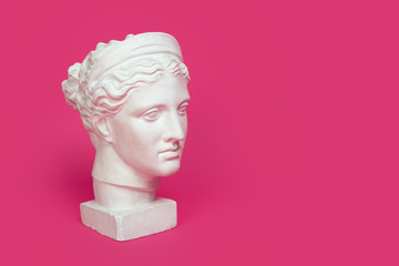 Marble head of young woman, ancient Greek goddess bust isolated on pink background with space for...