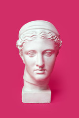 Marble head of young woman, ancient Greek goddess bust isolated on pink background