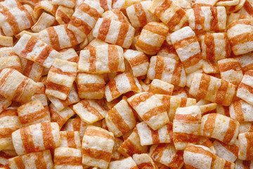 Food background. Chips in the form of bacon. Oblong striped potato chips. Studio light.