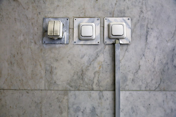 Four white household electric switches on a marble wall