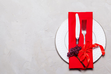 Valentines day table setting with fork, knife, plate and red dinner napkin on grey background, Top...