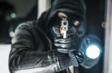 Einbrecher mit Pistole und Taschenlampe
