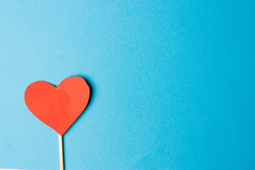 paper red heart on a stick, blue background