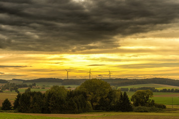 Windenergieanlagen im Sonnenuntergang mit aufziehendem Unwetter