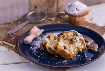 Muffins sprinkled by powdered sugar on white wooden desk.