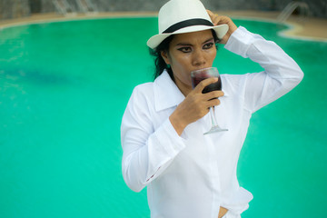 Sexy woman in white shirt posing on the swimming pool