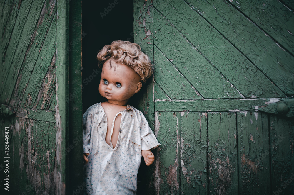 Wall mural An old scary doll peeps out from behind the gate and looks forward. The concept of exit from self-isolation, quarantine associated with the pandemic of the COVID-19 coronavirus.