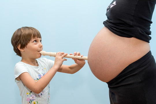 Child play the flute on a pregnant woman 