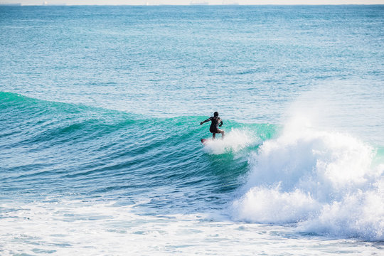 Surfer on blue wave in ocean.