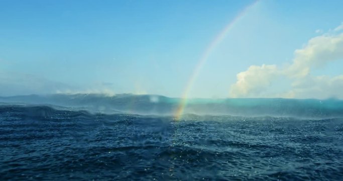 Ocean wave breaking with waterdroplets and beautiful rainbow