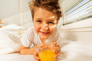 Happy boy with glass of fresh juice in his bedroom