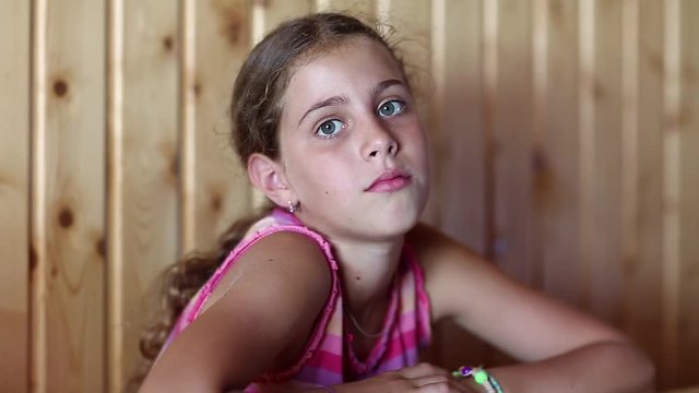 Pretty girl sits at the table and looks at the camera. Beautiful girl looking at the camera