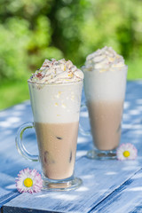 Cold coffee with whipped cream in sunny garden