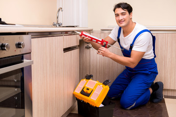 Young repairman working at the kitchen