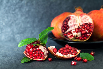 Fresh red pomegranate and seed  with leaves over black stone