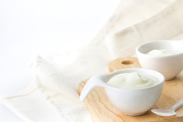 Close up natural creamy white yogurt in cup on wooden plate