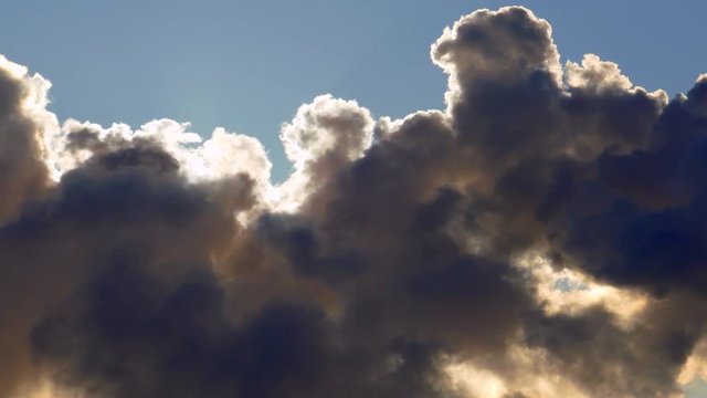 Sun squeezes between thick clouds with silver lining.
