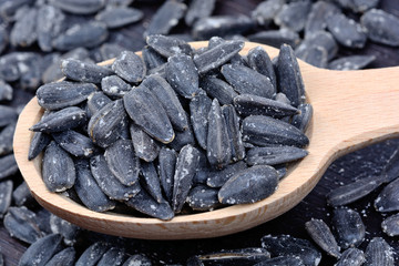 Black sunflower seeds in a wooden spoon