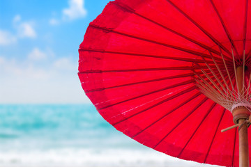 Red umbrella on blurred beach background