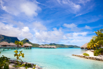 Beautiful beach on Bora Bora island in French Polynesia.  Thatched villas / bungalows over water. ...