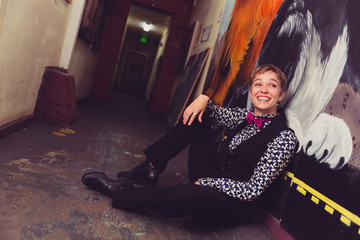 Young woman dressed in shirt and bow tie in a grungy, urban location with graffiti