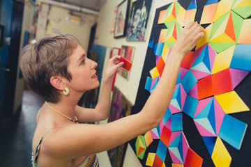 Young caucasian woman dressed in colorful bohemian style in a grungy, urban location featuring...