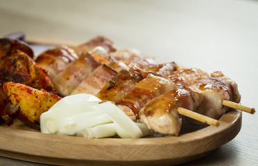 Brochette with baked potatoes - tasty chicken breast brochette wrapped in thin slices of meaty bacon, condiments on the side