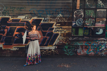 Young caucasian woman wearing bohemian skirt and top in a grungy, urban location