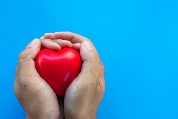 Obraz premium man hands giving red heart on coloured background