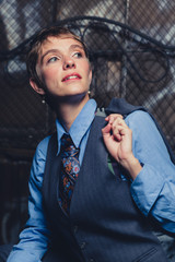 Young androgynous woman dressed in mens clothing in a grungy, urban outdoor location