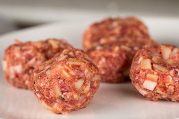 Minced meatballs on a plain white plate, tasty seasoned raw meat special