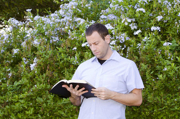 Naklejka na ściany i meble Man focused reading the Bible outside alone. 