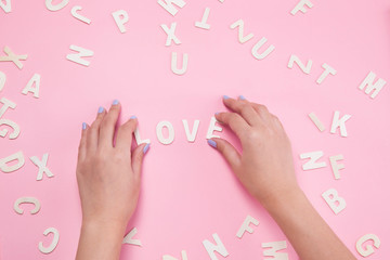Woman hand sorting letters LOVE on pink.