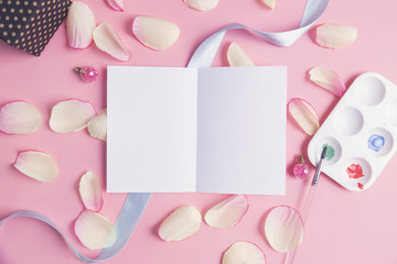White paper with pink petals on pastel background.